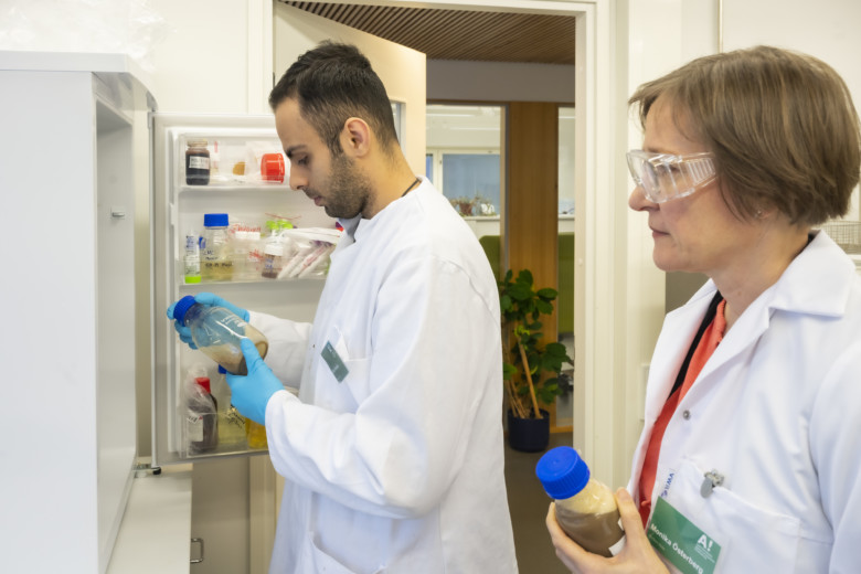 Researcher Erfan Kimiaei stands beside Professor Monika Österberg in front of the fridge storing the component used to produce plastic at Aalto University laboratory.