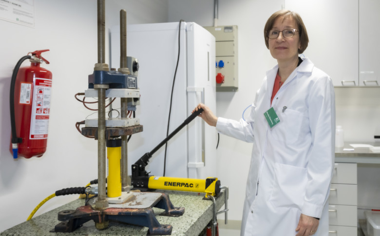 Image of a pillar-type drilling machine used as a hydraulic press to press a film. Professor Monika Österberg standing next to the machine.