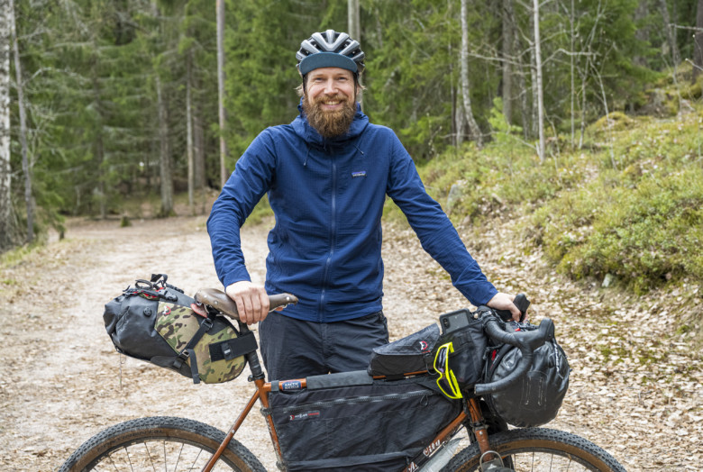 Taneli Roininen standing behind his bike on a dirt road.